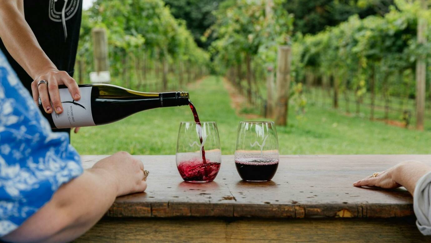 Red wine being poured in front of vineyard