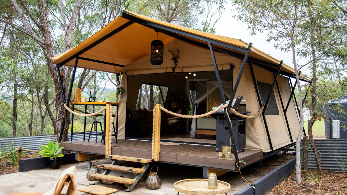 a picture of a luxury safari tent with deck and stairs set in a bush setting