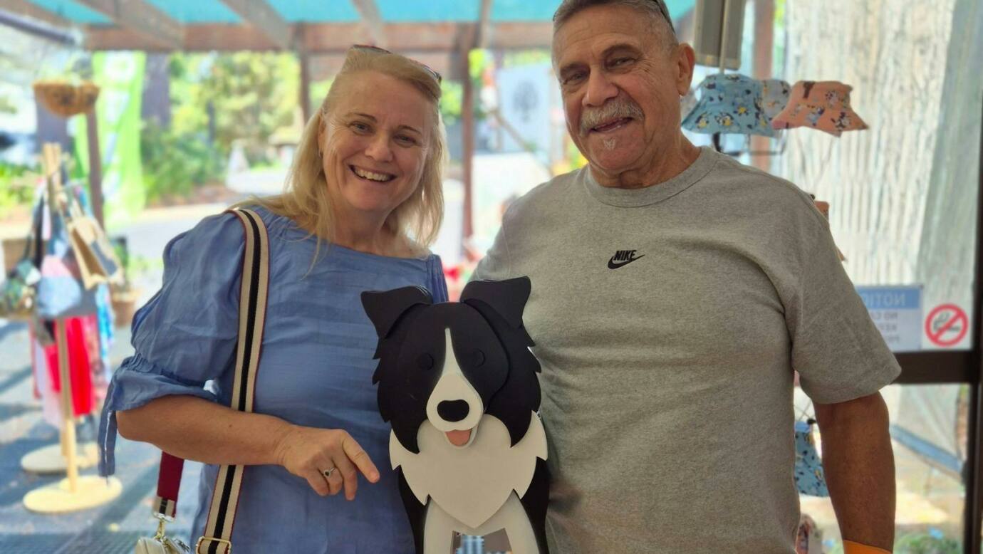 A smiling man and woman indoors holding a decorative black-and-white dog-shaped planter